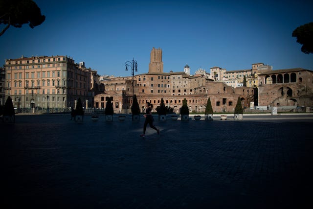 Una mujer corre junto al Foro romano durante la cuarentena para frenar la expansión del nuevo coronavirus.