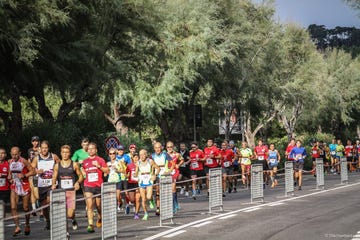 group of runners participating in a race on a treelined street