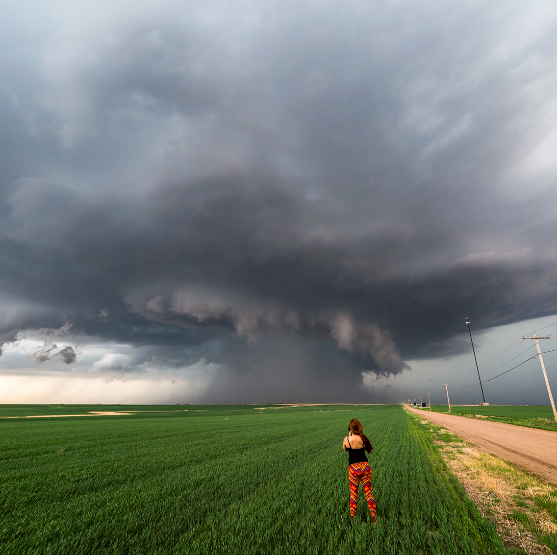 woman storm watching in field