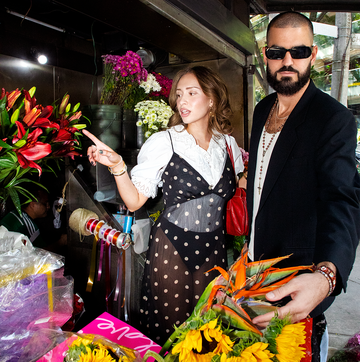 a man and woman standing next to a bouquet of flowers