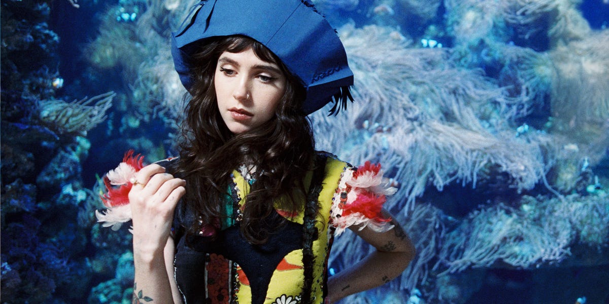 a person in a colorful outfit stands against a vibrant underwater backdrop a person in a colorful outfit stands against a vibrant underwater backdrop