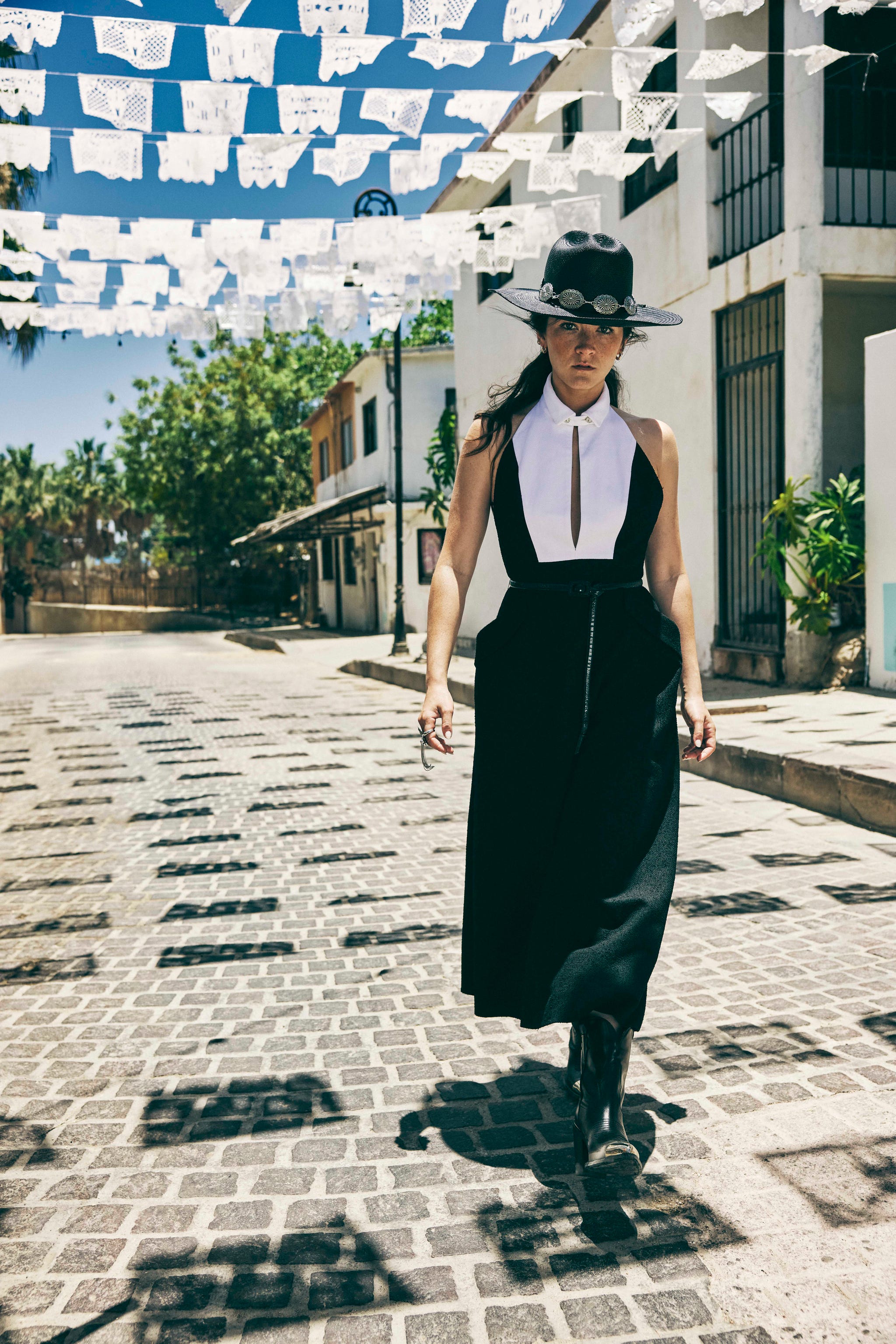 woman in black and white dress and cowboy hat walking on street