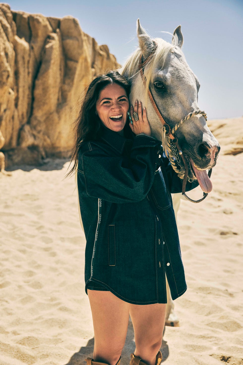 woman in denim laughing next to horse