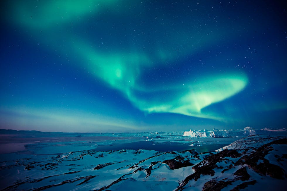 aurora borealis over a snowcovered landscape and icy waters