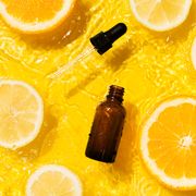 vitamin c serums  cosmetic bottle product serum vitamin c with orange and lemon flat lay on yellow background clean water splashing