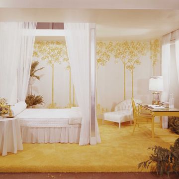 Een slaapkamer met geel tapijt en hemelbed