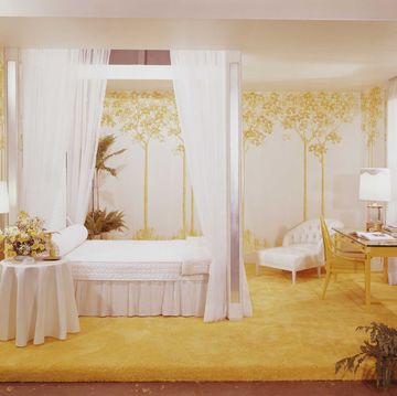 Een slaapkamer met geel tapijt en hemelbed