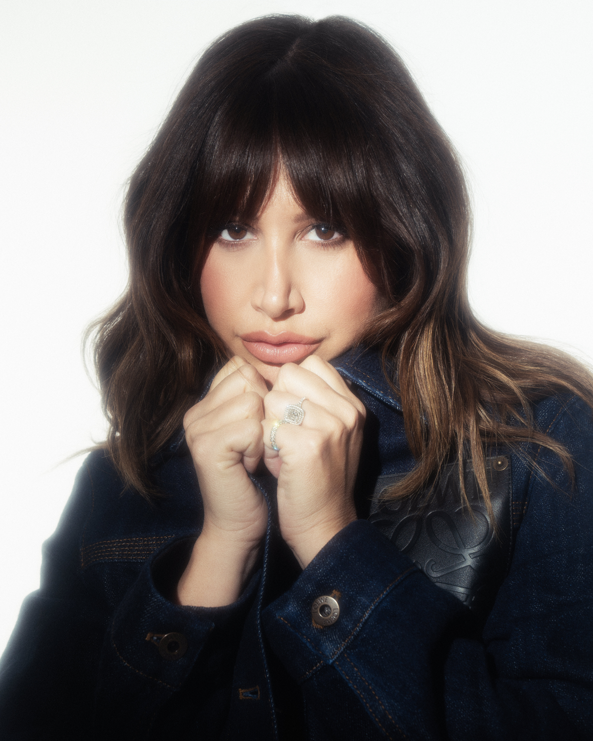 a person holding their hands together showcasing jewelry and denim attire