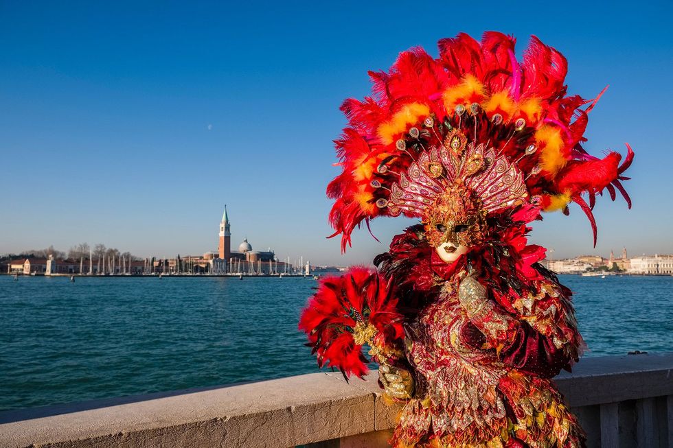 Een carnavalsganger poseert bij het Grand Canal in Veneti De traditionele Venetiaanse carnavalsmaskers worden ambachtelijk vervaardigd en prachtig versierd