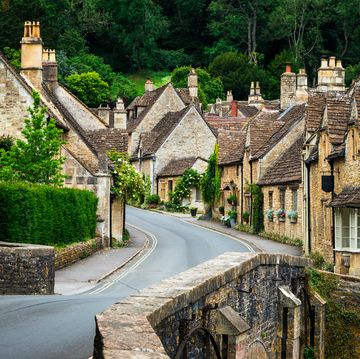 color image depicting a traditional english village in the cotswolds area of southwest england the cosy little brick cottages line the narrow road, and there is also a quaint bridge spanning a little stream room for copy space