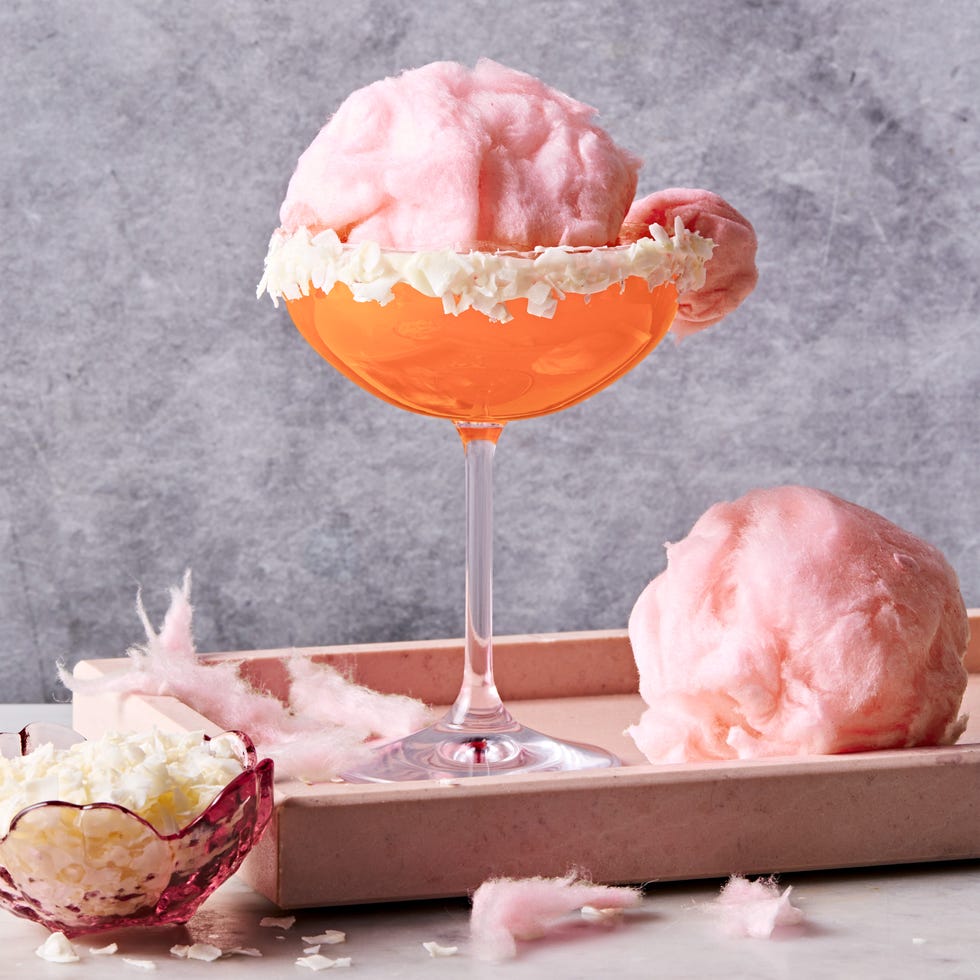 pink cocktail with a coconut flake rim and pink cotton candy floating