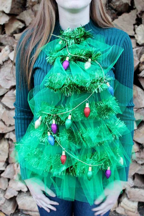 green ugly christmas sweater with tulle and garland in shape of a tree and christmas light ornaments hanging off the garland