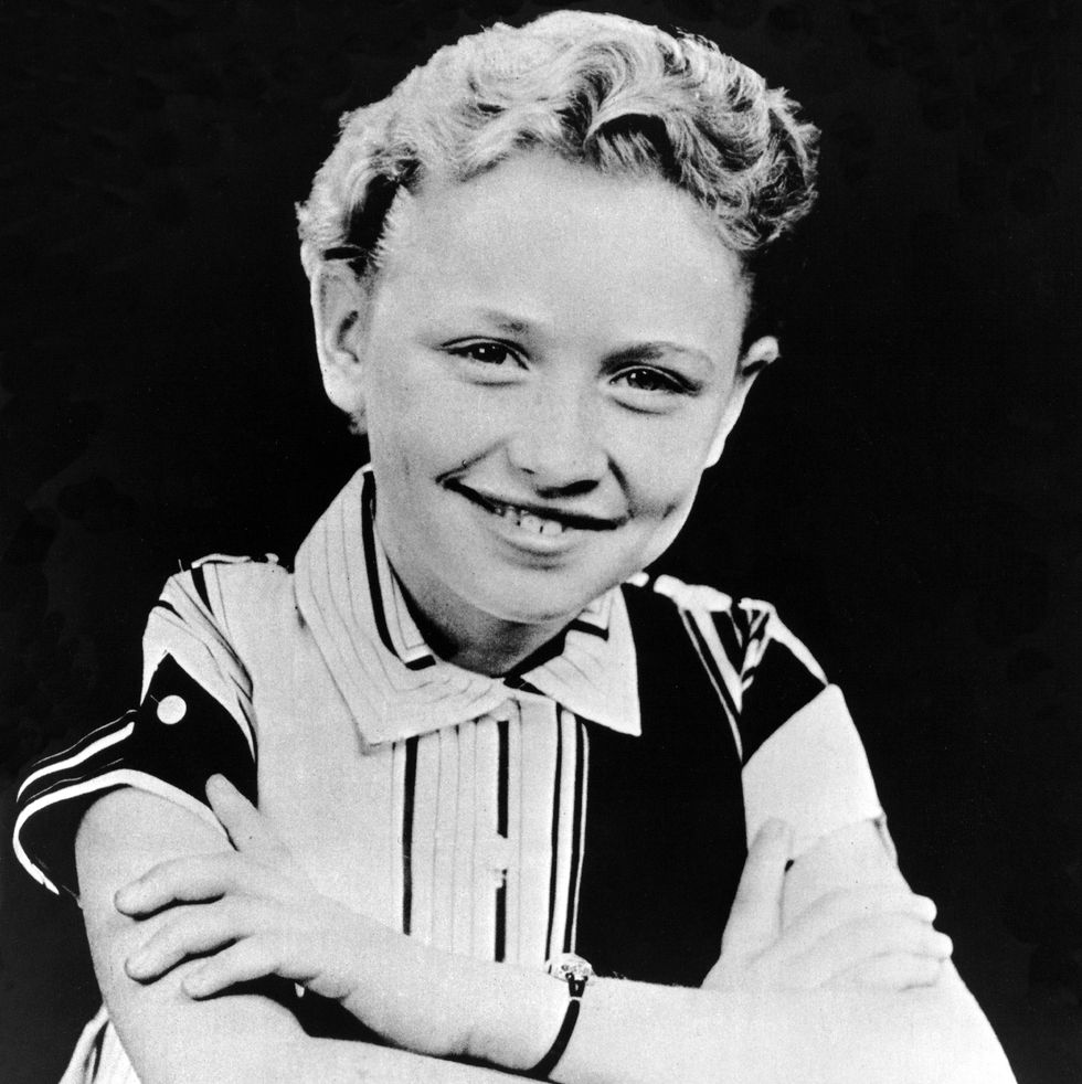 a black and white photo of a young dolly parton with her arms crossed, smiling at the camera