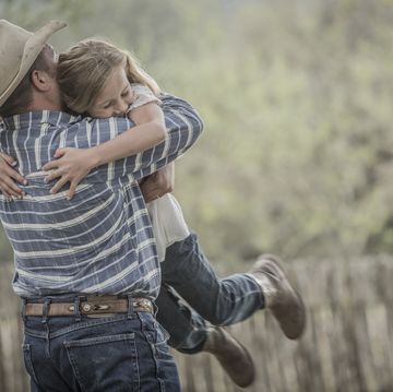 father wearing cowboy hat lifting and hugging daughter