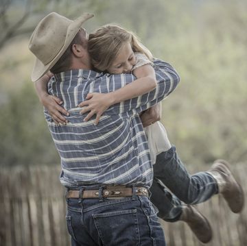 father wearing cowboy hat lifting and hugging daughter