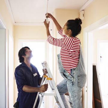 couple changing light bulb while renovating home