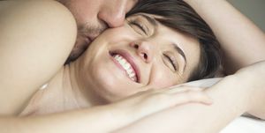 Couple cuddling in bed, husband kissing wife