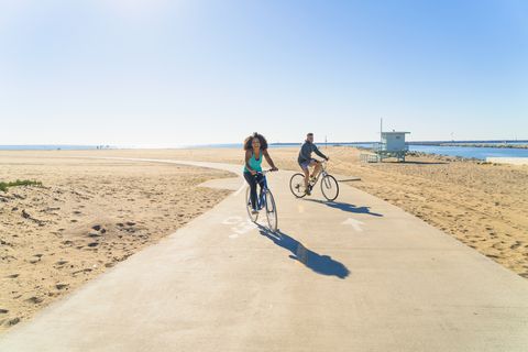 couple cycling along pathway at beach