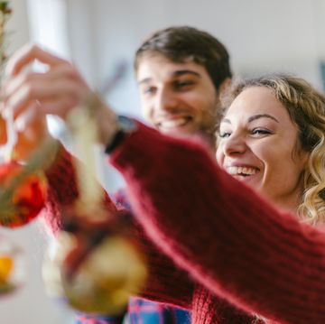 una pareja decora feliz un arbol de navidad