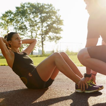 couple doing sit ups in city park early morning