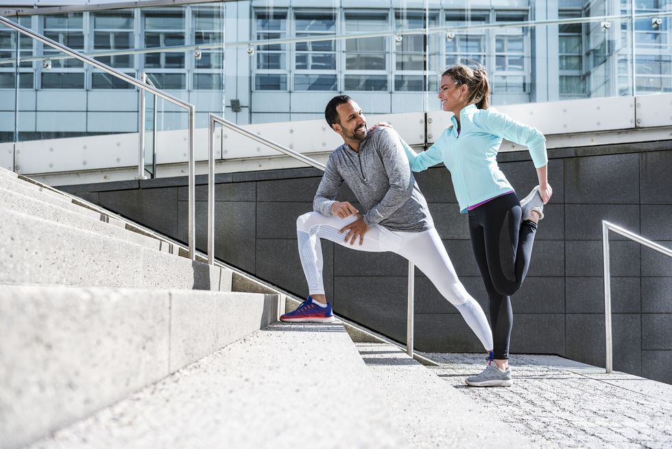 couple doing stretching exercise on stairs in the city