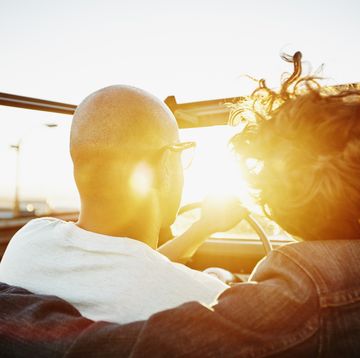 couple driving convertible at sunset