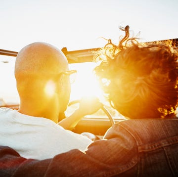 couple driving convertible at sunset