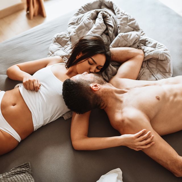 couple engaged in kissing and romantic activity while still wearing underwear in bed