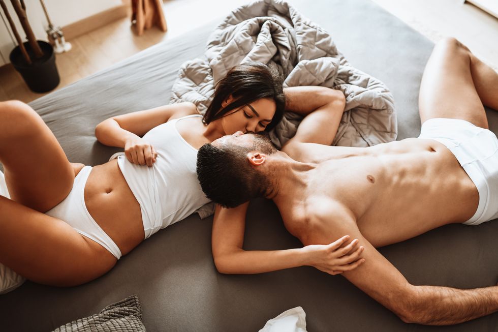 couple engaged in kissing and romantic activity while still wearing underwear in bed