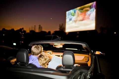 a couple having fun in their car at a drive in theater