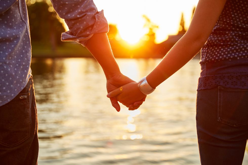 Couple holding hands next to river.