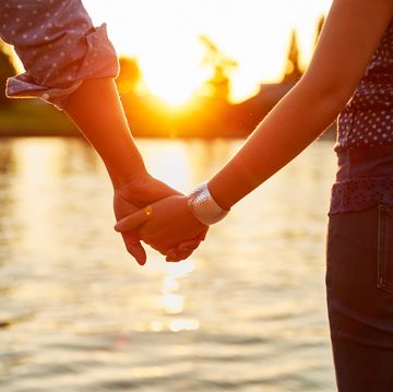 couple holding hands next to river