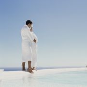 couple in dressing gowns embracing at edge of outdoor pool, side view