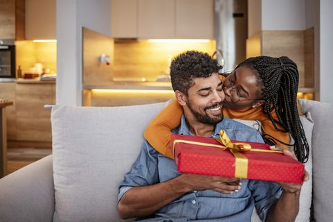 a black couple giving each other a red wrapped gift