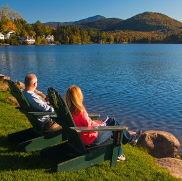 couple in wooden adirondack chairs watching over mirror lake in the adirondack mountains at lake placid, northern new york in the united states