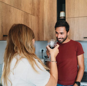 a couple is drinking red wine in the kitchen