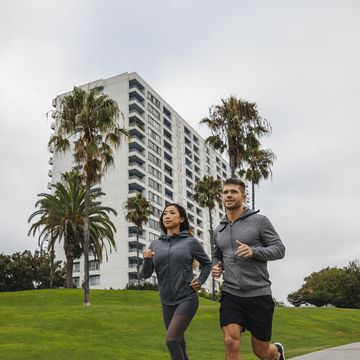 couple jogging at park against sky