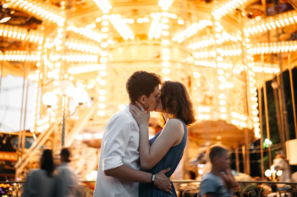 couple kissing near the marry go round in the park