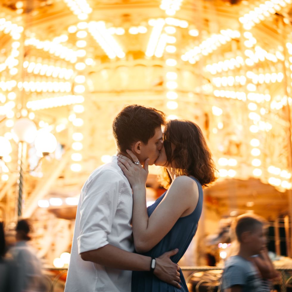 couple kissing near the marry go round in the park