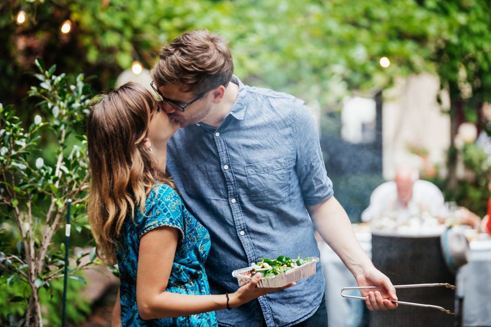 couple kissing while cooking at family bbq