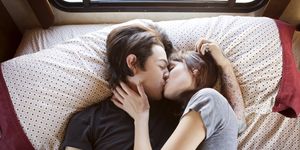 Couple kissing while lying on bed in camper van