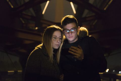 Couple Looking At Mobile Phone under a metal bridge
