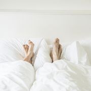 a couple lying in a bed with their feet sticking out from underneath the covers