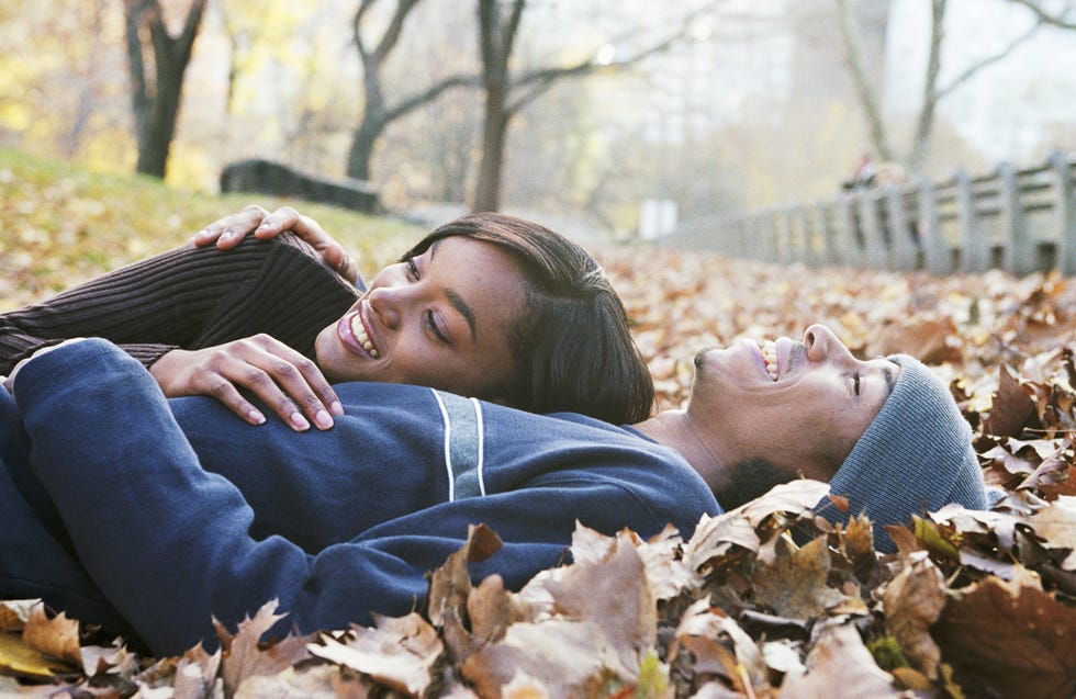 Couple lying on autumn leaves in park, side view Couple lying on autumn leaves in park, side view