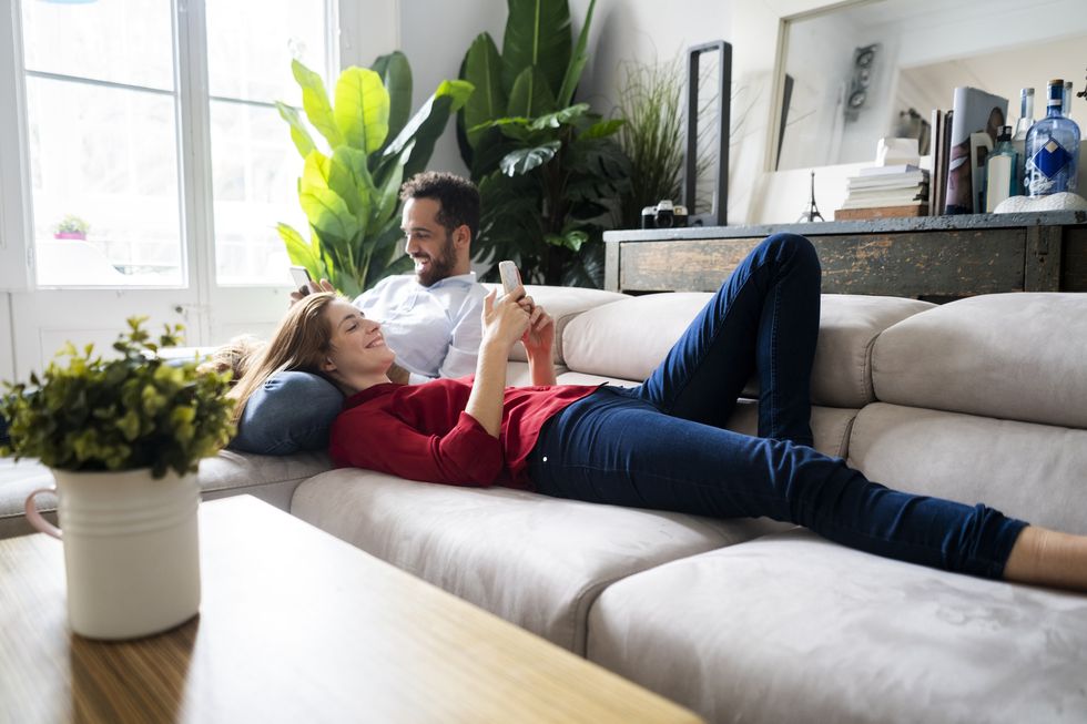 couple lying on couch, using heir smartphones