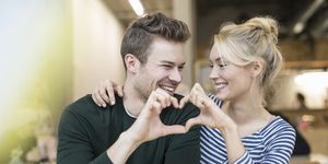 Couple making heart hands together in cafe