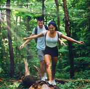 couple passing over a broken tree during their hike in the forest
