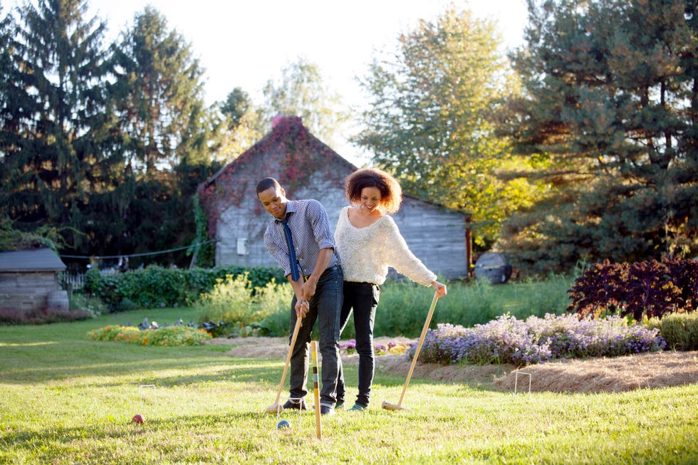 couple playing croquet on grassy field