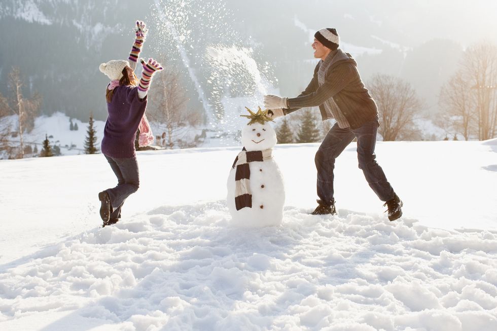 couple making snowman and playing in snow
