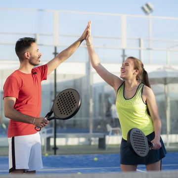 couple playing paddle tennis in court, hi five fair play gesture